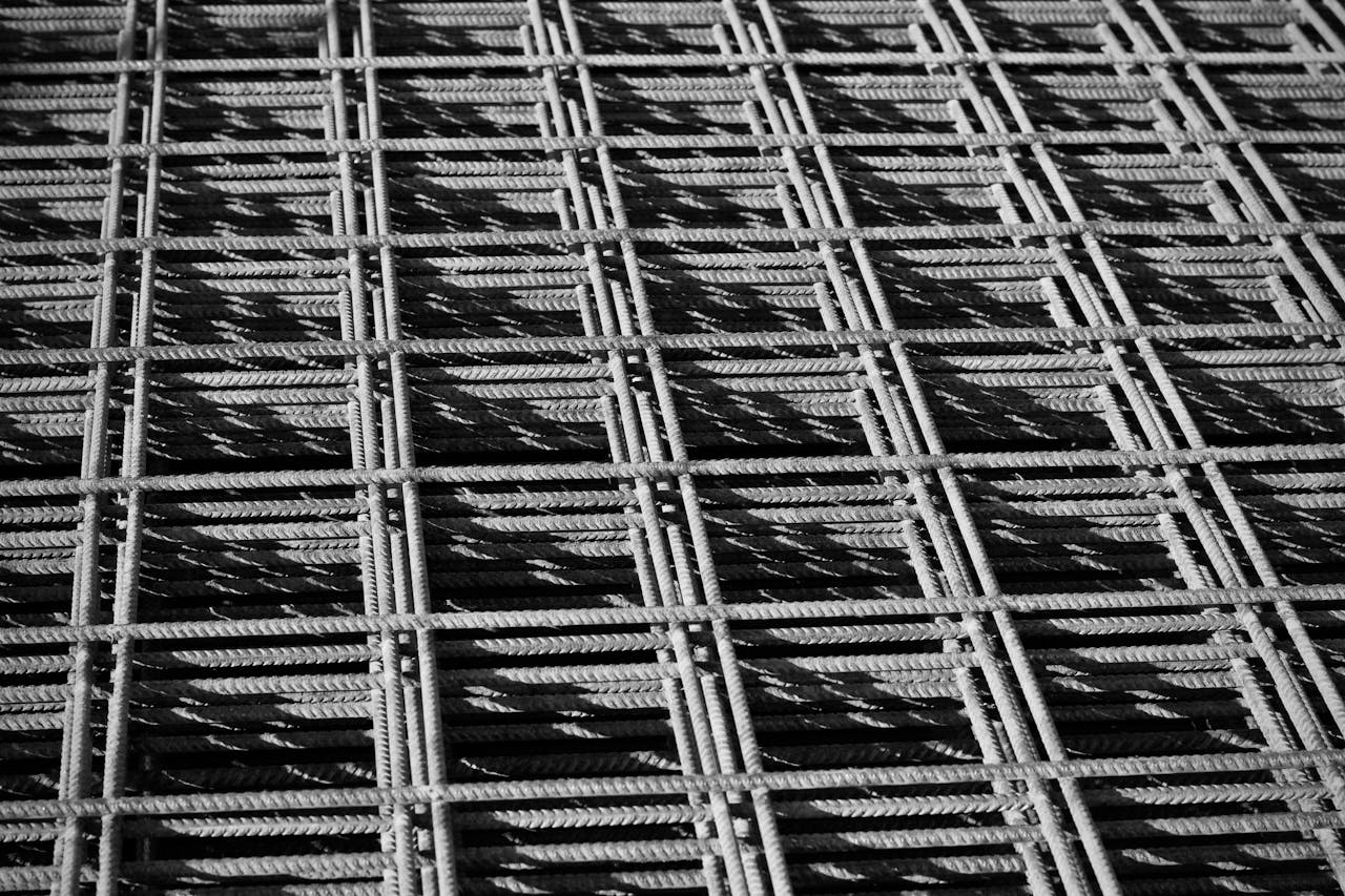 Close-up of a steel rebar grid creating a geometric pattern in black and white.